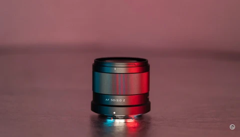 Camera lens with blue and red gel lighting against a pink background.