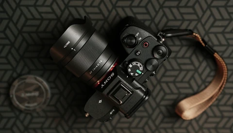 Sony mirrorless camera with attached lens and brown leather strap on geometric patterned surface.