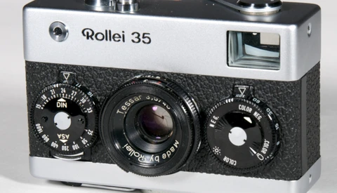 Rollei 35 compact film camera with white and black body, showing dual control dials and Tessar lens.