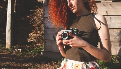 Person holding a vintage rangefinder camera in golden hour sunlight.