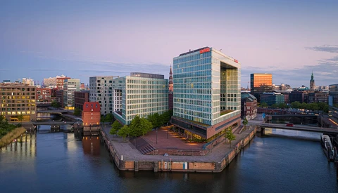 Modern waterfront cityscape at dusk with contemporary office buildings surrounding a central canal basin.