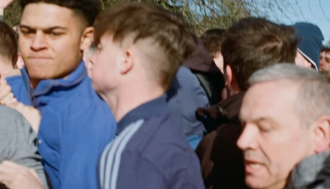 Group of young men gathered outdoors in casual clothing during daytime.