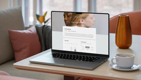 Laptop displaying a professional portfolio website with two portrait photographs and resume information.