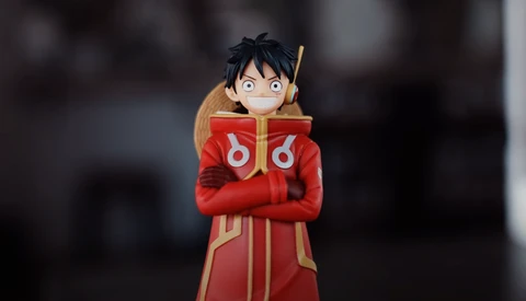 Illustration of an anime character with black hair wearing a red and gold coat with crossed arms.