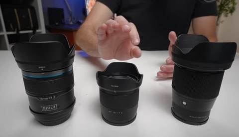 Three camera lenses displayed on a white surface with a person's hand gesturing between them for comparison.