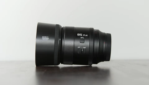 Sirui 85mm F1.4 lens with hood mounted, displayed on light gray surface.