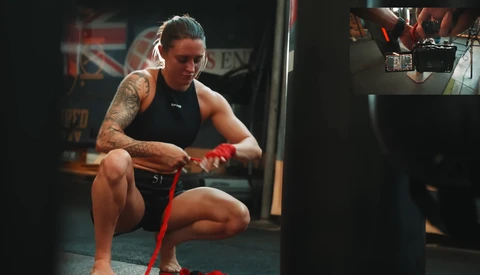 Athlete in black tank top performing a squat with a red resistance band in a gym.