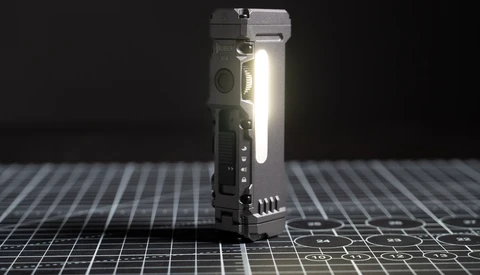 Compact tactical flashlight with integrated controls illuminated against a dark grid surface.