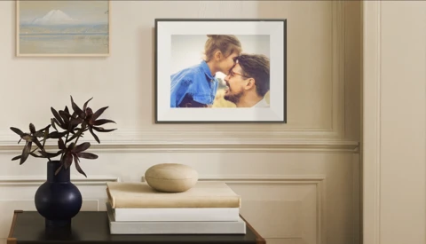 Framed portrait photograph displayed above a console table with books and a decorative vase.