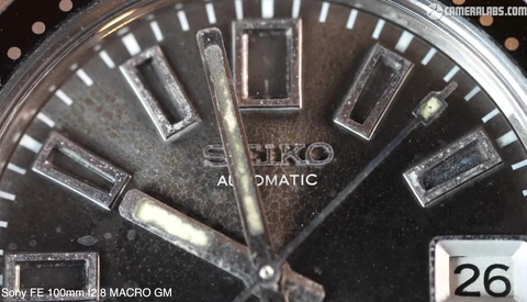 Close-up macro photograph of a Seiko Automatic watch face with dark dial and applied hour markers.
