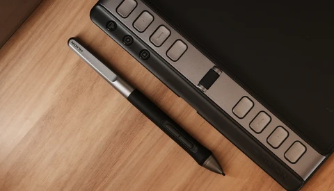 Digital stylus and power strip arranged on wooden surface next to dark background.