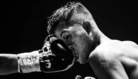 Boxer receiving a punch to the face during a match against black background.