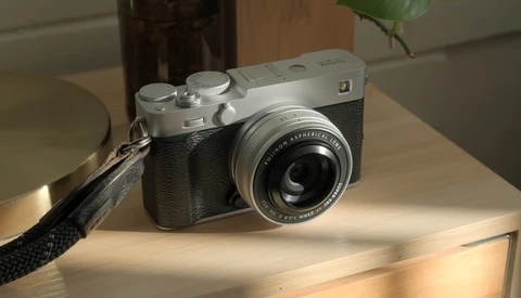 Fujifilm Instax rangefinder camera with black leather grip displayed on wooden surface in daylight.