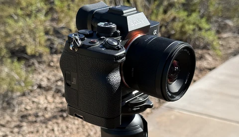 Sony mirrorless camera with prime lens mounted on tripod in outdoor setting.