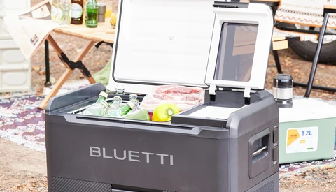 Bluetti portable power station with open lid displaying control panel and battery display outdoors.