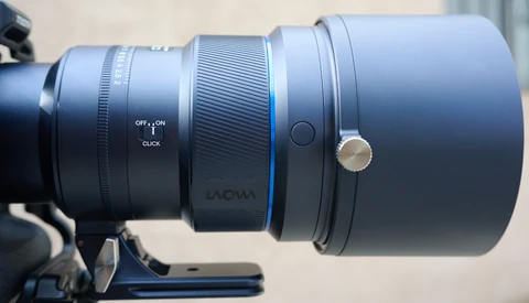 Close-up of a telephoto lens mounted on a camera, showing focus ring, depth of field markings, and manual focus controls.