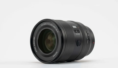 Black telephoto zoom lens with visible focus ring and distance scale on neutral background.