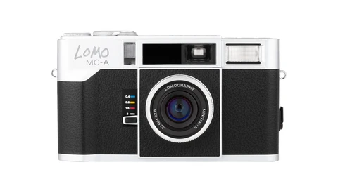 Lomo LC-A film camera with white top plate, black leatherette body, and Lomography lens against white background.