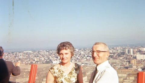 Two people standing on an elevated observation deck overlooking a sprawling cityscape at dusk.