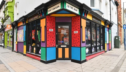 Vibrant corner storefront with bold primary colors, geometric patterns, and black framing on a brick street.