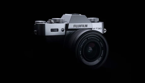 Fujifilm X-T30 mirrorless camera with kit lens against black background.