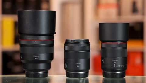 Three Canon RF-mount lenses of varying focal lengths arranged side by side on a reflective surface.