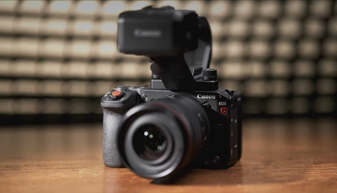 Canon EOS R5 mirrorless camera with external recorder mounted on top, positioned on wooden surface.