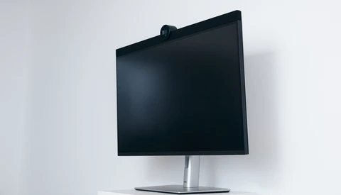 Modern monitor with black display on silver pedestal stand against white wall.