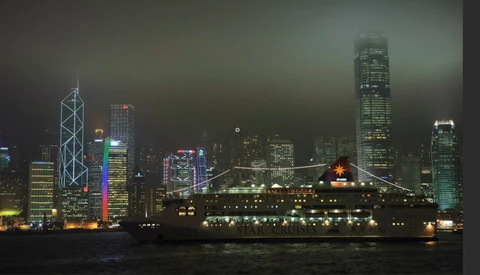 Night cityscape with illuminated skyscrapers reflected in dark water below.