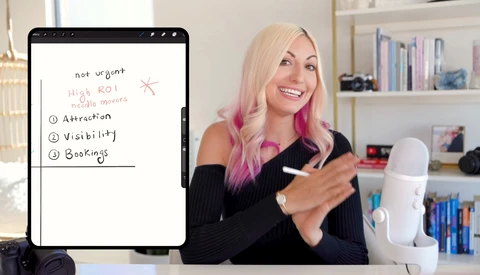 Woman with blonde and pink hair presenting a digital tablet displaying a handwritten list about high ROI priorities including attraction, visibility, and bookings.