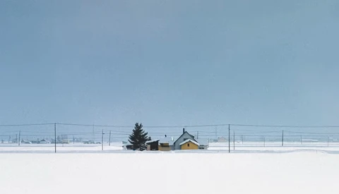 Isolated farmhouse with evergreen trees in snowy field under clear blue sky.