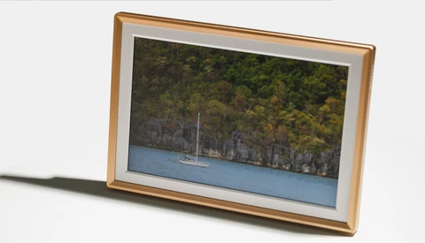 Wooden picture frame displaying a sailboat anchored near a forested coastline with limestone cliffs.