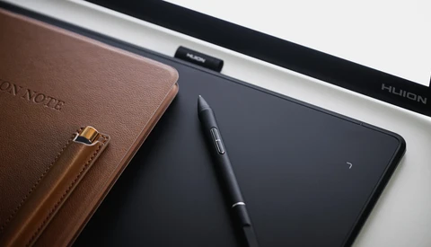 Brown leather notebook with stylus pen and digital tablet on white desk surface.