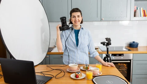Content creator in a kitchen studio setting up lighting equipment for food photography.