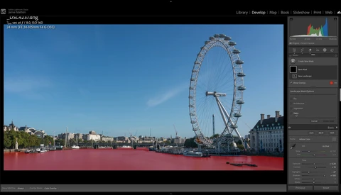 London Eye ferris wheel and Thames riverbank under clear blue sky, with red-tinted water in foreground.