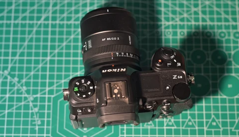 Overhead view of a Nikon Z6II mirrorless camera with an attached zoom lens on a green cutting mat.