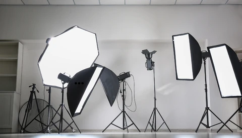 Professional studio lighting setup with softboxes, reflectors, and tripod stands arranged in a white studio space.