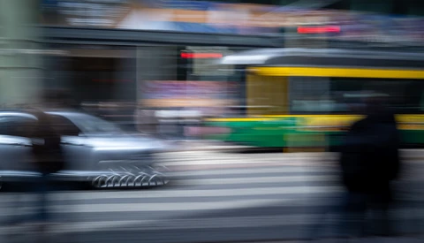 Motion blur photograph of urban street scene with moving bus and vehicles.