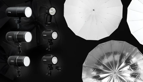 Professional studio lighting setup with multiple LED panel lights and large diffusion umbrellas arranged on black background.