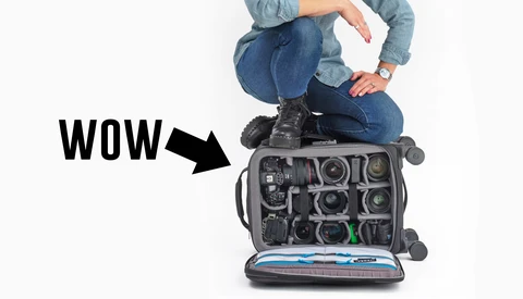 Camera gear organizer bag with multiple lens compartments, viewed from above with person sitting on top.