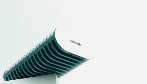 Curved architectural structure with parallel ridged lines against a light background.
