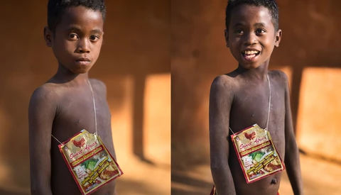 Young child holding a packaged food item, smiling at camera in warm indoor lighting.
