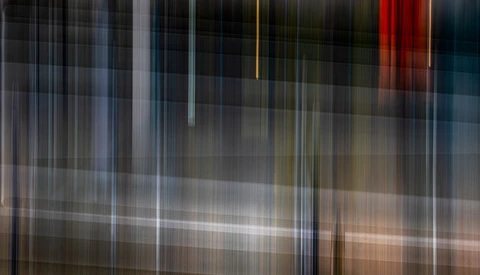 Abstract vertical light streaks and blurred architectural elements with warm and cool color tones.