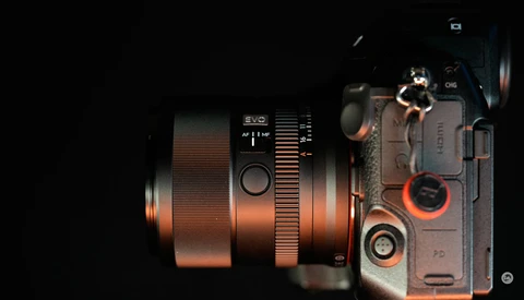 Overhead view of a mirrorless camera with an attached telephoto lens against a black background.
