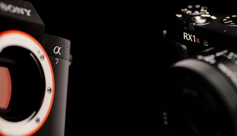 Sony Alpha 7 and RX1R mirrorless cameras positioned against a black background with dramatic side lighting.