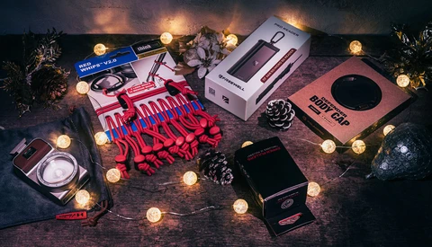 Flat lay of photography and beauty products arranged with warm string lights and decorative pinecones.