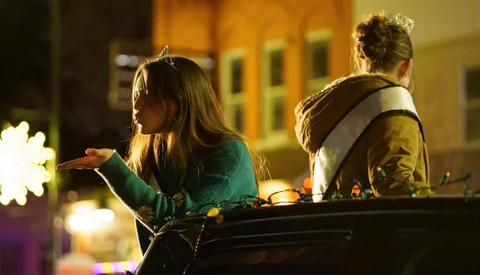 Two people sitting outdoors at night, illuminated by warm ambient lighting and decorative lights in the background.
