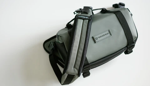 Gray and black camera bag with shoulder straps and zippered compartments, displayed against white background.