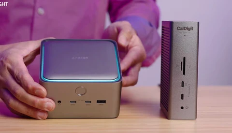 Person in magenta shirt holding compact Anker power bank beside CalDigit desktop device.