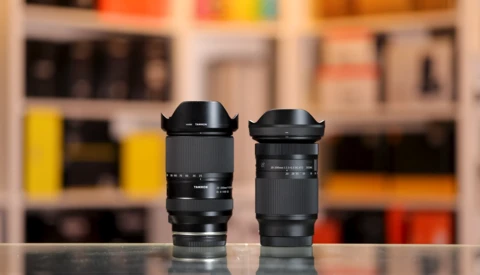 Two black telephoto lenses with lens hoods displayed side by side on a reflective surface.